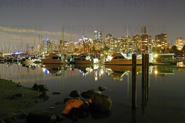 Illuminated skyscrapers and pleasure boats reflected in the calm water