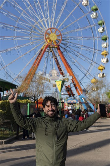 Portrait of latino man in an amusement park posing happy with the ferris wheel in the background