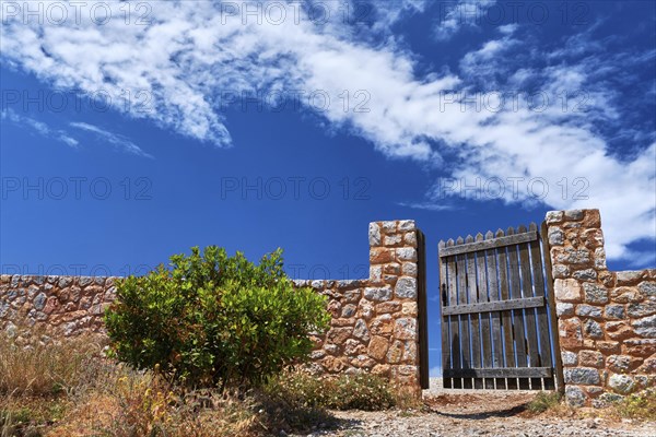 Countryside landscape. Rustic stone wall fence and aged black timber wicket door. Great blue sky with awesome clouds. Concept of opening opportunities