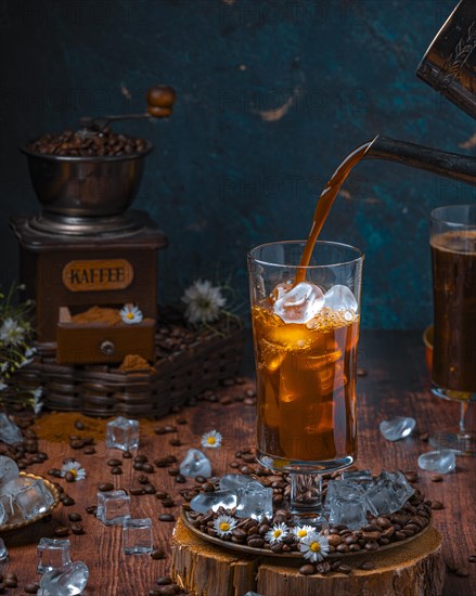 Coffee is poured into glass with ice cube cubes