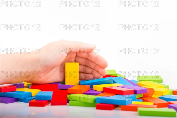 Hand playing with colored domino on white background