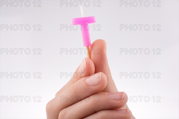 Color candle in hand on sticks writes the letter T