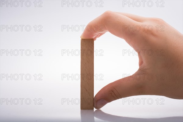 Hand holding wooden domino on a white background