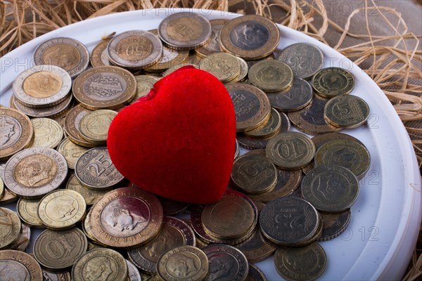 Turkish Lira coins by the side of a red color heart shaped object on white background