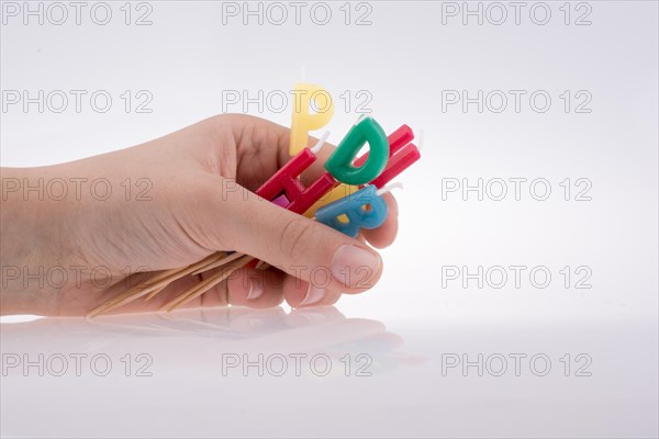 Hand holding letters made of candles on sticks