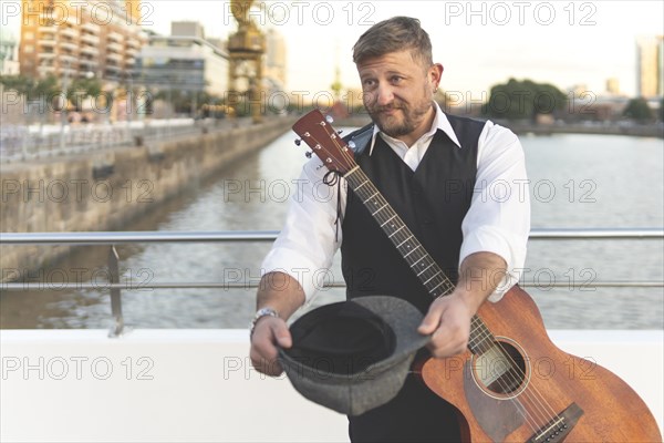 Guitarist asking for tips on a bridge over a river