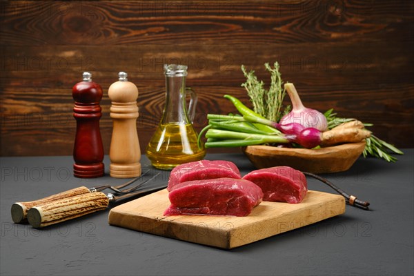 Tree pieces of raw ribeye steaks cut on slices on wooden cutting board