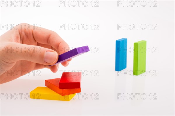 Hand playing with colored domino on white background