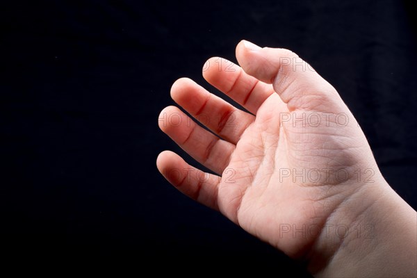 Five fingers of a child hand partly seen in black background