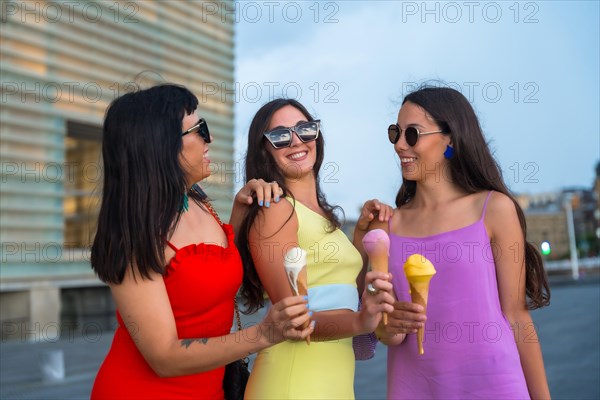 Young female friends eating ice cream on summer vacation by the beach having fun