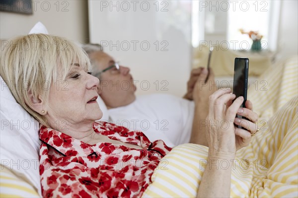 Elderly couple lying in bed together in their bedroom