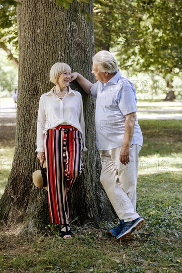 Summery dressed older woman together with her grey-haired man in the park