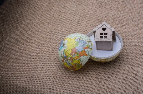 Model house and a globe on a linen canvas