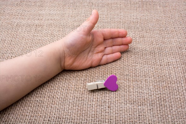 Clothespin with a heart shaped object in hand on canvas