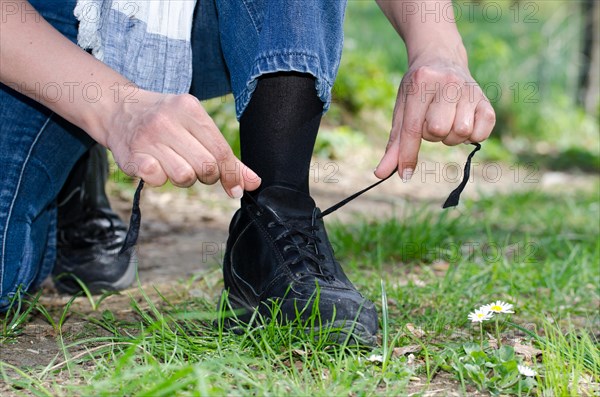 Woman Tying Shoelaces on a Path with Grass