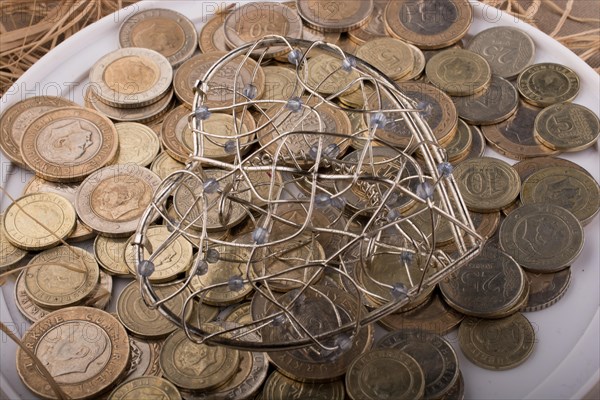 Turkish Lira coins by the side of a red color heart shaped object on white background