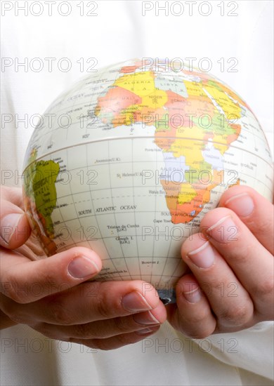 Child holding a small model globe in hand on white background