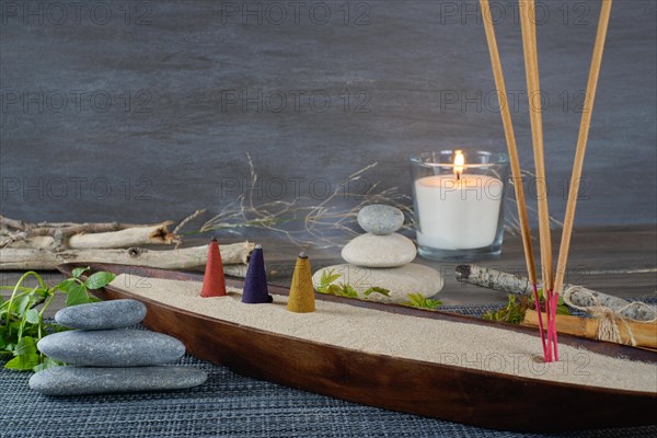 Various types of incense smoking in a wooden bowl with sand