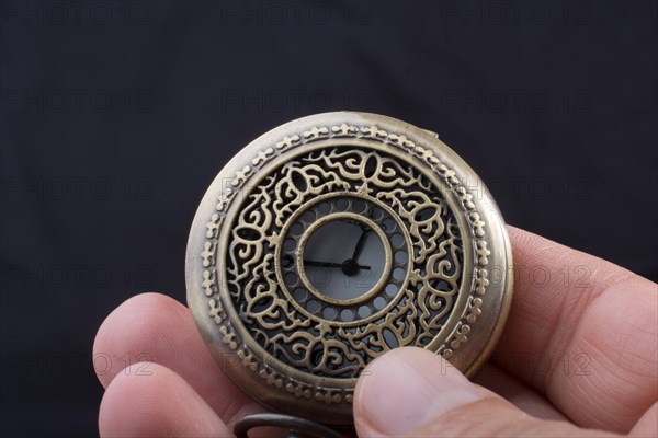 Retro style pocket watch in hand on black background