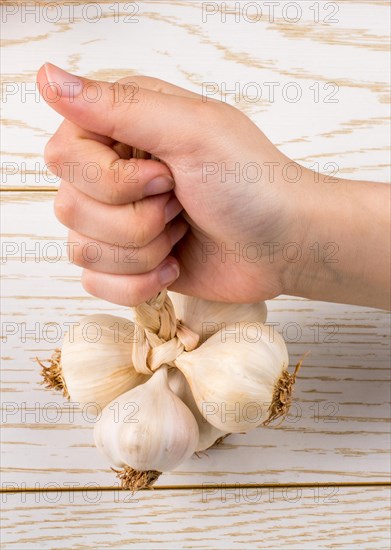 Hand holding cloves of garlic on a wooden texture