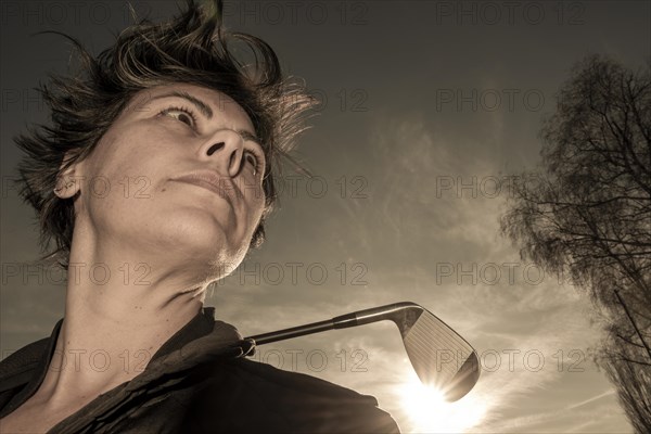 Golfer Leaning Her Golf Club on Her Shoulders with Sunlight