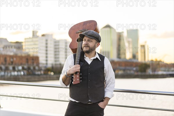 Portrait of a musician looking away while holding his guitar on his shoulder