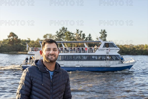 Latin man posing in front of a boat on the river
