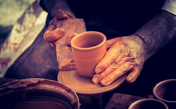 Potter`s hands shaping up the clay of the pot