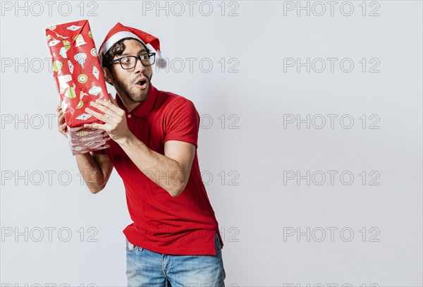 Christmas man holding and listening a gift box. Christmas guy holding and listening a gift box. Excited christmas people holding and listening a gift. Concept of guessing a christmas gift