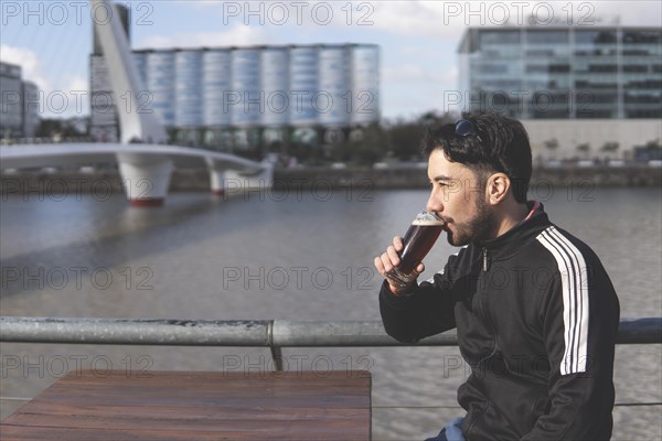 Latin tourist drinking beer at an outdoor bar in Puerto Madero