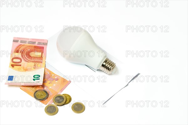 Light bulb on an electricity bill and banknotes and coins on a white background.concept of electricity price increase