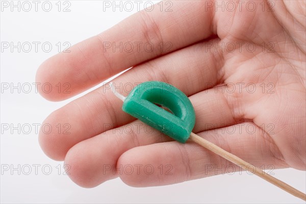 Color candle in hand on sticks writes the letter D