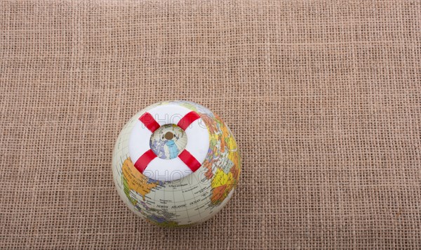 Life preserver on top of globe on canvas background