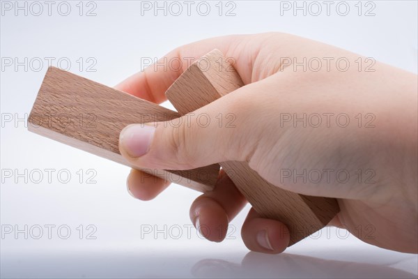 Hand holding wooden domino on a white background