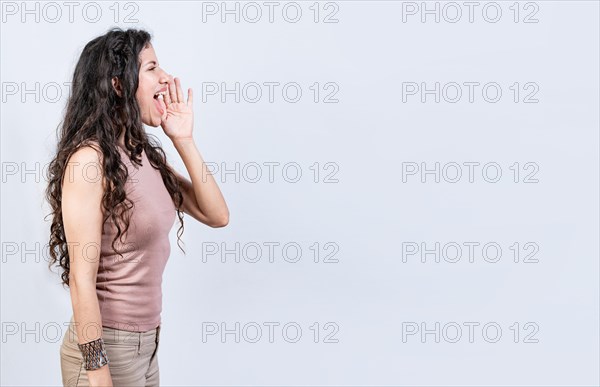 Beautiful girl shouting a promotion isolated. Side profile young woman shouting an announcement. Latin woman shouting an advertisement