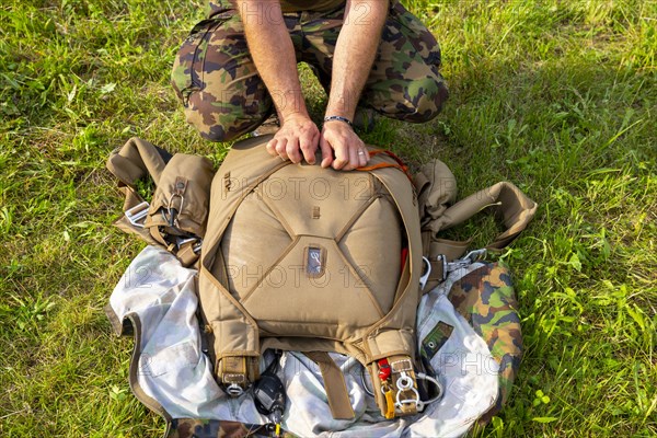 Military Parachuter Standing on the Grass with His Parachute in Switzerland