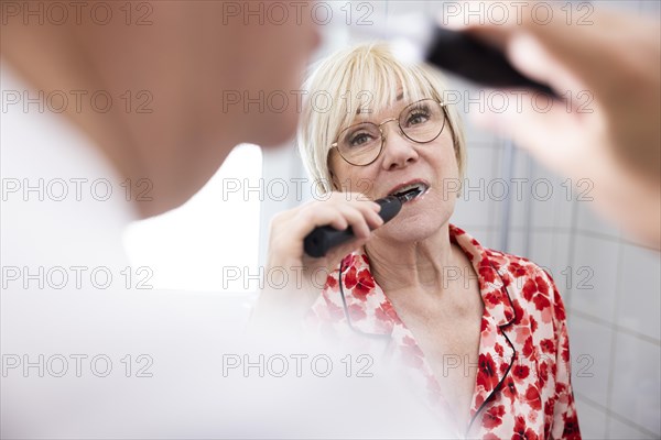 Elderly couple brush their teeth together in the bathroom