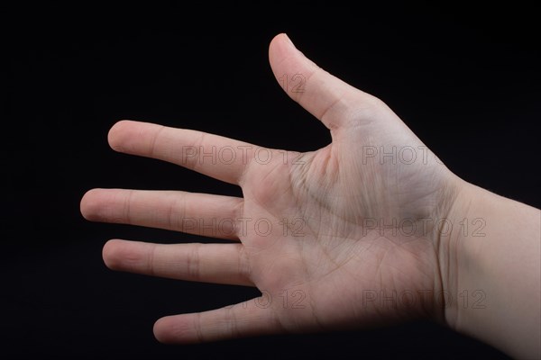 Five fingers of a child hand partly seen in black background