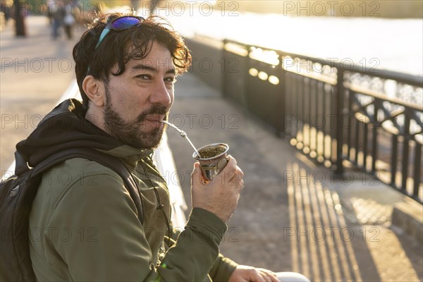 Latin man enjoying the sunset at the river while drinking mate