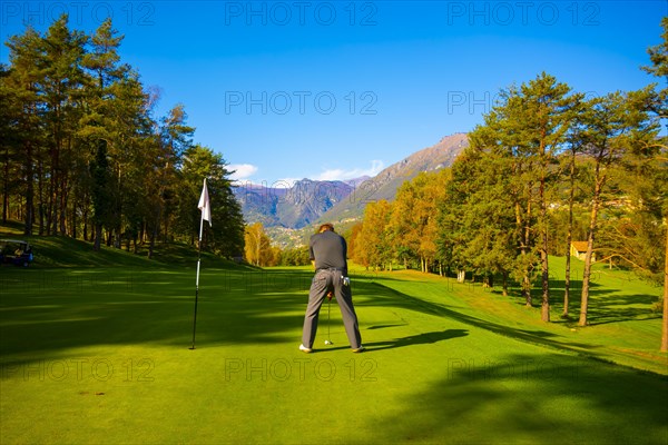 Golfer on Putting Green on Golf Course Menaggio with Mountain View in Autumn in Lombardy