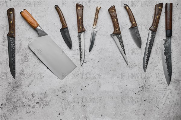 Various types of knives scattered on concrete background