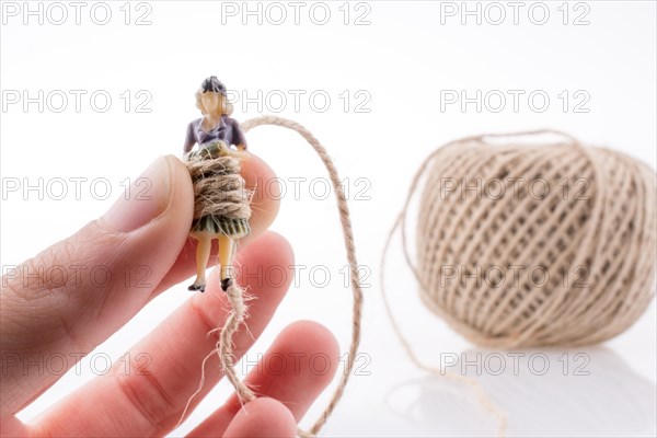Woman figure in hand beside a linen spool of thread on a white background