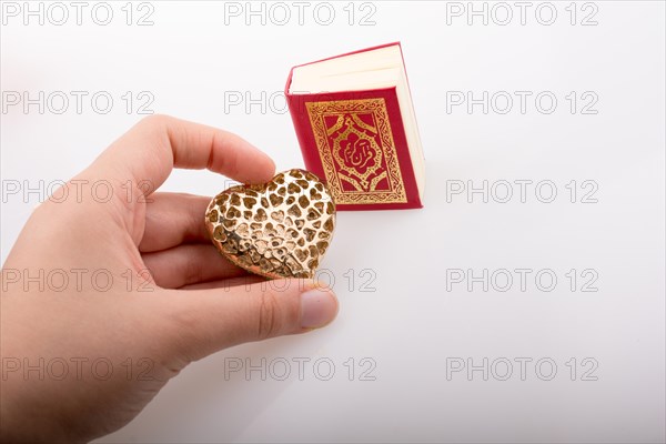 Hand holding Heart shape and Islamic Holy Book Quran