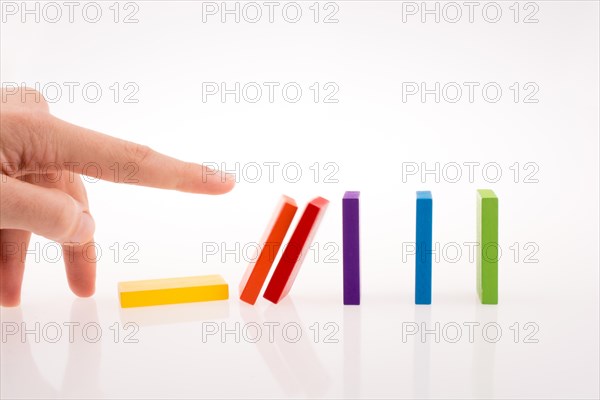 Hand playing with colored domino on white background