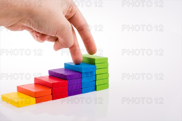 Hand playing with colored domino on white background