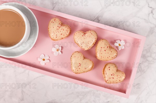 Heart shaped French macaron sweets on pink tablet with coffee cup