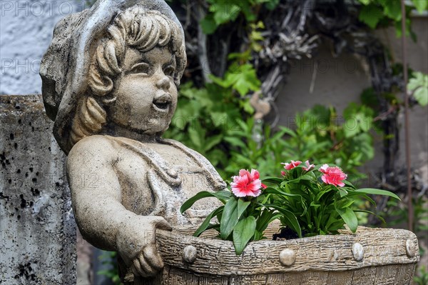 Childlike stone figure with flower basket and garden carnations