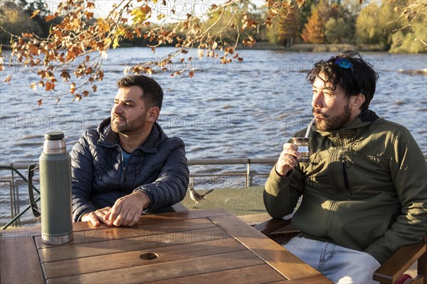 Two friends enjoying the sunset while drinking mate