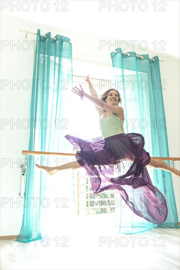 Woman Jumping and Doing the Splits Against a Window with Curtain with Transparent Skirt