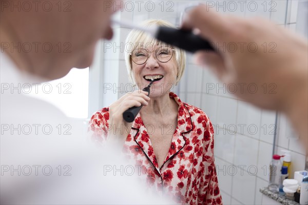 Elderly couple brush their teeth together in the bathroom